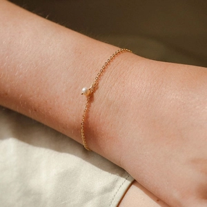 Nahaufnahme eines 14K vergoldeten Titanstahl-Armbands mit einer runden weißen Perle