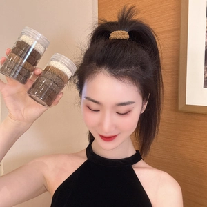 Detail of high-elasticity hair ties in earth tones shown in clear jar packaging