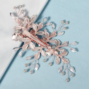 Détail d'une pince à cheveux de mariée or rose avec feuilles, perles et pince crocodile