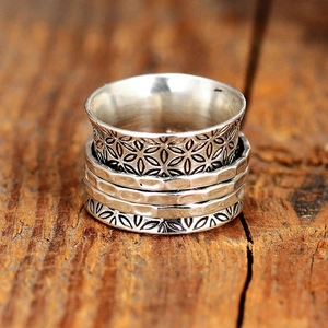 Vintage silver-tone wide ring with multi-layer floral engravings on textured wood