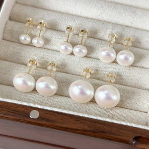 Detail of five pairs of white pearl earrings with pink luster in a wooden jewelry box