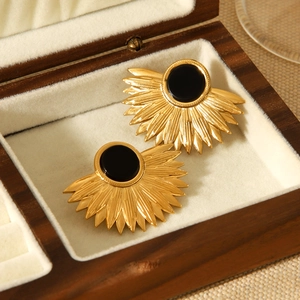 Detail of 18K gold stainless steel leaf earrings with black round gemstone on beige lining