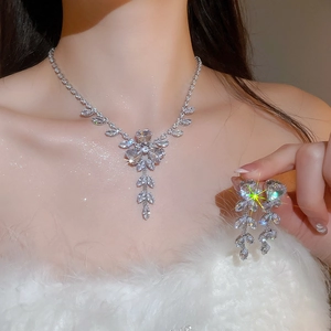 Detailed view of silver zircon flower tassel necklace and earrings set on a female model
