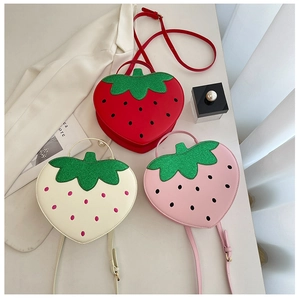 Detailed view of three strawberry-shaped crossbody bags in red, pink and white leather