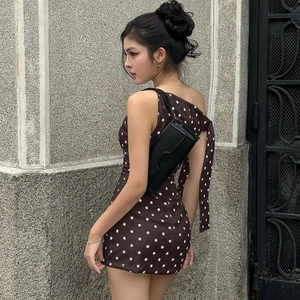 Detail view of brown and white polka dot bodycon dress with black shoulder bag