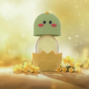 Close-up of a cartoon style facial ice roller massager with green head and yellow base