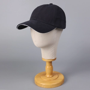 Détail d'une casquette en coton noir avec bordure en dentelle blanche sur la visière
