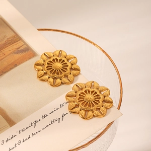 Détail de boucles d'oreilles fleurs dorées avec texture martelée sur carte vintage