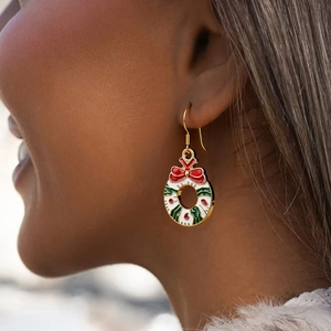 Festive Christmas wreath earrings with colorful enamel drop on gold hooks worn by a model
