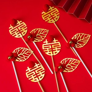 Traditional Chinese wedding cake topper with red pom-poms and golden Xi character decor
