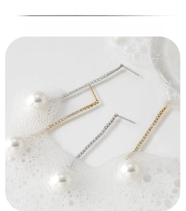 Close-up of long zircon tassels and round white pearls on gold and silver earrings