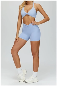 Macro detail of a light blue halter sports bra with knot decor and V-waist gym shorts