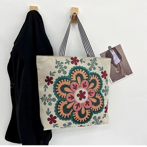 Detail of vintage canvas tote bag featuring floral mandala embroidery and striped handles
