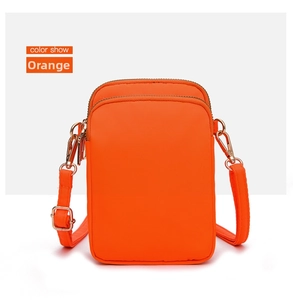 Detail of bright orange nylon crossbody phone bag with dual gold zipper compartments
