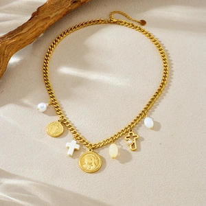 Close-up of vintage gold relief coin, pearl charms and cross pendants on a thick chain
