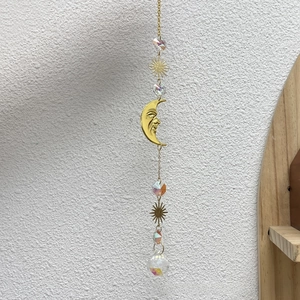 Detail of crystal suncatcher with golden crescent moon and sunburst prism hanging