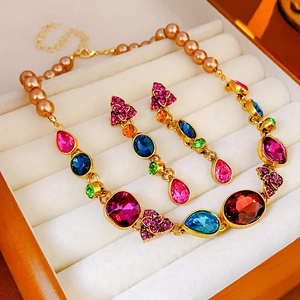 Detailed macro view of vintage gold necklace and teardrop earrings with multi-color gems