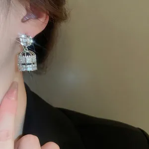 Elegant silver birdcage drop earrings with cubic zirconia on a female model