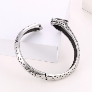 Détail du bracelet tête de léopard argenté avec motifs gravés noirs et acier poli