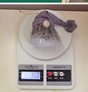 Close-up showing a grey knitted Christmas gnome with golden lanyard on a digital scale