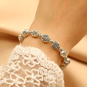 Macro detail of vintage silver rose charm bracelet with delicate floral engravings