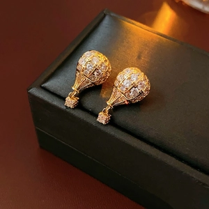 Détail de boucles d'oreilles montgolfière dorées avec zircons sur boîte à bijoux