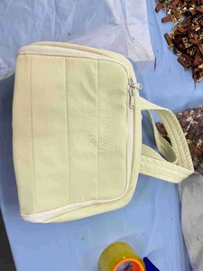 Top view of beige quilted travel toiletry bag with white zipper in a workshop setting