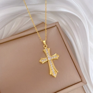 Detailed view of a gold cross pendant with clear cubic zirconia on a luxury chain