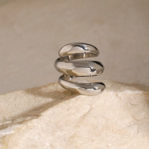 Macro shot of triple-layer spiral stainless steel ring on natural stone background