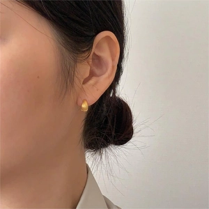 Close-up of elegant gold ribbed hoop earring worn by a model in a minimalist style