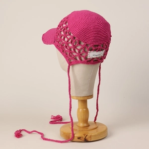 Detail of fuchsia handmade crochet baseball cap with hollow mesh and braided tassels