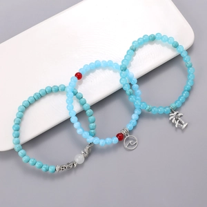 Detalle de pulseras de cuentas con colgantes de caballito de mar, ola y palmera