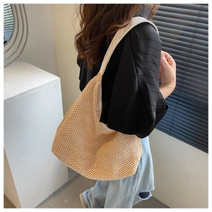 Close-up of beige woven straw shoulder bag with a white wide strap worn by a model