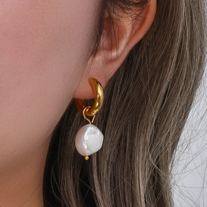 Vue détaillée d'un mannequin portant une créole dorée avec un pendentif en perle baroque
