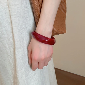 Macro detail of dark burgundy acrylic geometric bangle with smooth polished finish