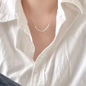 Minimalist 925 sterling silver cube necklace on model with white linen shirt