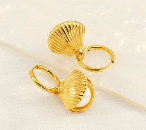 Close-up of golden shell earrings with a white pearl inside an open shell detail