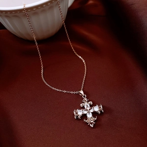 Macro shot of rose gold gothic cross pendant with white zircon stones on red velvet