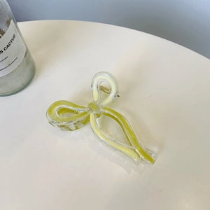 Macro shot of large lemon yellow and clear ribbon bow hair claw with gold spring