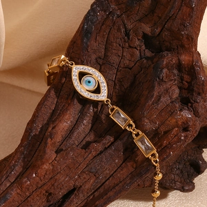 Detailed close-up of 18K gold plated evil eye bracelet with white zircon on dark wood