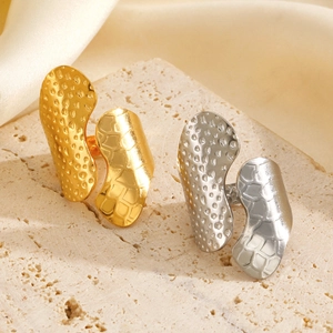 Wide 18K gold and silver chunky rings with hammered textures on travertine stone