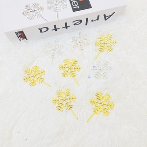 Golden and silver snowflake cake toppers displayed on a white fluffy surface