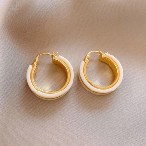 Detail shot of vintage gold C-shaped hoop earrings with white enamel finish in light luxury style