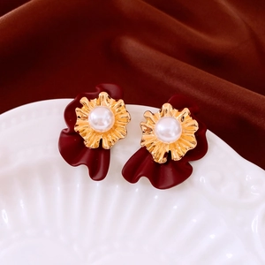 Détail de boucles d'oreilles rétro avec pétales rouge vin, dorure et perle centrale
