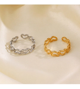 Detail of adjustable hollow heart rings in gold and silver finish on silk background