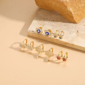 Detail view of 6 pairs of gold evil eye stud earrings and colorful gemstone hoop sets