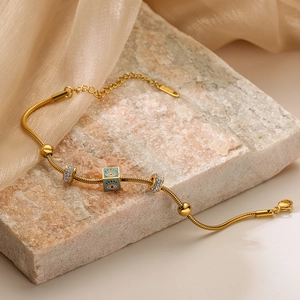 Gold plated snake chain bracelet with blue enamel evil eye charm on stone and silk