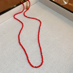 Detail of red faceted glass bead necklace with golden lobster clasp and extender chain