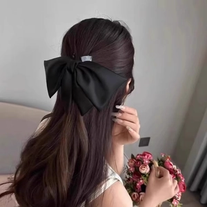 Elegant large black satin bow hair clip for women shown on a model from the back view