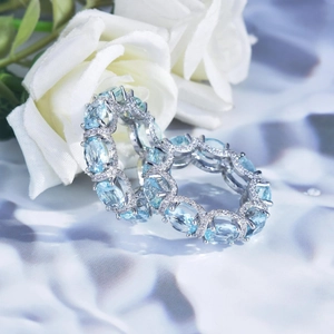 Detailed close-up of stacked silver eternity rings with oval blue gems and small diamonds